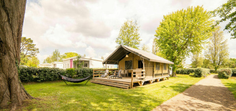 Safari-lodgetent aan Camping Kost Ar Moor in Frankrijk met houten veranda, hangmat en veel groen.