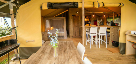 Interieur van de Safari lodge tent op Camping Kost Ar Moor in Frankrijk met houten meubels en gezellige sfeer.