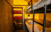 Foto interior de la tienda Safari lodge en Camping Kost Ar Moor, Francia, con literas y estantería visibles.