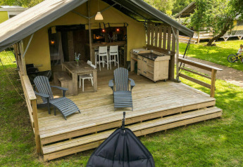 Safaritent lodge op Camping Kost Ar Moor in Frankrijk, met houten terras en kinderen die fietsen.