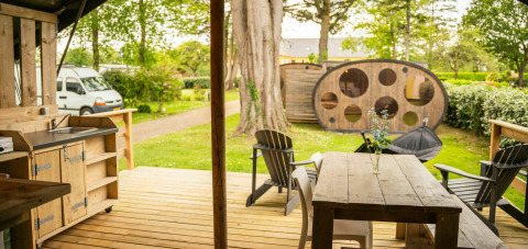 Buitengedeelte van een Safari Lodge tent met houten terras en zitruimte op Camping Kost Ar Moor in Frankrijk.