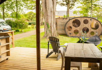 Buitengedeelte van een Safari Lodge tent met houten terras en zitruimte op Camping Kost Ar Moor in Frankrijk.