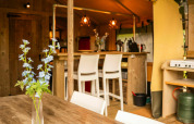 Interior de una tienda Safari lodge en Camping Kost Ar Moor, Francia, con muebles rústicos de madera y flores.