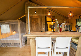 Tienda lodge safari en Camping Kost Ar Moor, Francia, con decoración en madera y ambiente acogedor.
