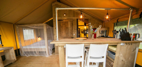 Safari-Lodge-Zelt auf Camping Kost Ar Moor in Frankreich mit gemütlicher Küche und Holzmöbeln.