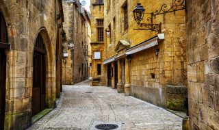Calle empedrada bordeada de edificios históricos cerca de Marcillac St. Quentin, Nouvelle-Aquitaine, Francia.