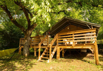 Safari Lodge + Teeny Lodge: Luxuriöses Safarizelt auf Holzplattform mit Hängematte im grünen, schattigen Garten.