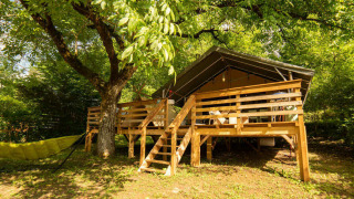 Safari Lodge + Teeny Lodge: Tienda safari elevada sobre plataforma de madera con hamaca, en entornos naturales verdes.
