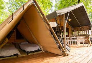 Safari Lodge und Teeny Lodge auf einer Holzterrasse, umgeben von Bäumen, bei Camping Les Tailladis in Frankreich.