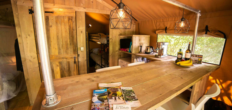 Vista interior de la tienda Safari Lodge + Teeny Lodge en Camping Les Tailladis, Francia, con decoración de madera.