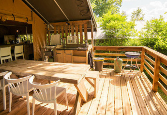 Terrazza esterna della Safari Lodge al Camping Les Tailladis in Francia con tavolo, sedie e barbecue.