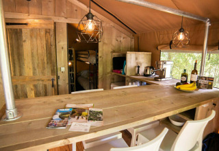 Vista interior de la tienda Safari Lodge en Camping Les Tailladis, Francia, con muebles rústicos de madera.