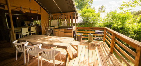 Buiten houten terras met eetruimte bij het Safari Lodge tent op Camping Les Tailladis in Frankrijk.