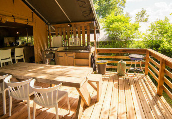 Buiten houten terras met eetruimte bij het Safari Lodge tent op Camping Les Tailladis in Frankrijk.