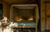 Foto interior de tienda Safari Lodge en Camping Les Tailladis, Francia, con muebles de madera y cama.
