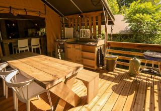 Buitenterras aan de Safari Lodge tent op Camping Les Tailladis in Frankrijk met houten zitmeubilair.