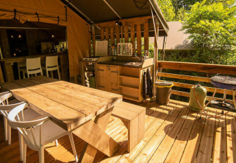 Buitenterras aan de Safari Lodge tent op Camping Les Tailladis in Frankrijk met houten zitmeubilair.