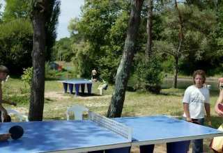 Børn spiller bordtennis udendørs ved Camping Les Tailladis, omgivet af træer og natur i Frankrig.
