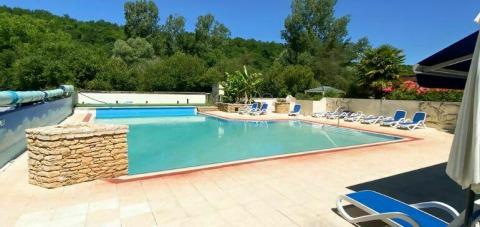 Outdoor swimming pool with sun loungers and green surroundings at Camping Les Tailladis, Nouvelle-Aquitaine.