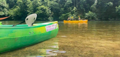 Canoeing at Camping Les Tailladis, Nouvelle-Aquitaine, France, with boats on a clear river amid lush forests.