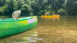Paseo en canoa en Camping Les Tailladis, Nouvelle-Aquitaine, Francia, entre un río claro y naturaleza verde.