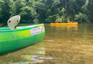 Canoeing at Camping Les Tailladis, Nouvelle-Aquitaine, France, with boats on a clear river amid lush forests.