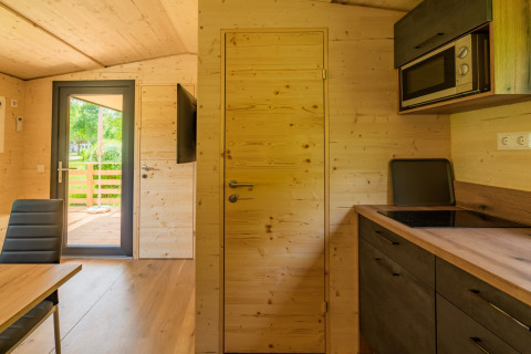 Interieur van een moderne houten lodge bij Wood Cubes op Drau Camping Sachsenburg, keuken en terras.
