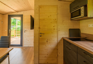 Interior de una cabaña moderna en Wood Cubes en Drau Camping Sachsenburg, cocina y vista a la terraza.