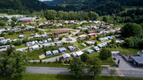 Aerial view of Camping Lac des Brenets holiday park in Neuchâtel, Switzerland, with caravans and lush greenery.