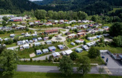 Aerial view of Camping Lac des Brenets holiday park in Neuchâtel, Switzerland, with caravans and lush greenery.
