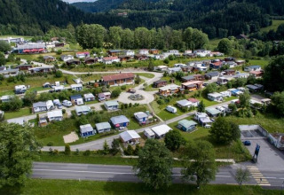 Luchtfoto van Camping Lac des Brenets, een vakantiepark in Neuchâtel, Zwitserland met caravans en veel groen.