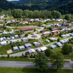 Vista aérea de Camping Lac des Brenets, un parque de vacaciones en Neuchâtel, Suiza, con caravanas y naturaleza.