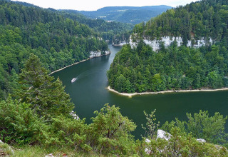 Vista panorámica del lago en Camping Lac des Brenets, Neuchâtel, Suiza, rodeado de bosque verde
