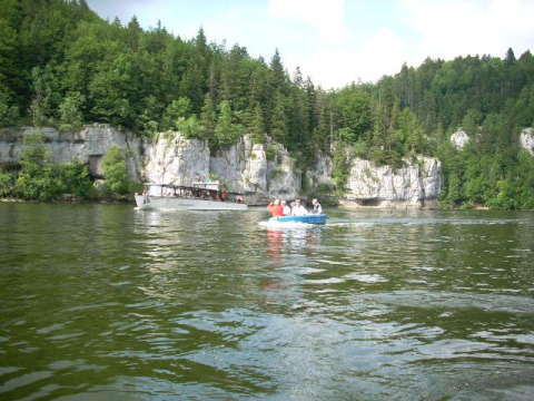 Boats on a scenic lake surrounded by cliffs and forest at Camping Lac des Brenets, Neuchâtel, Switzerland.