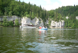 Boats on a scenic lake surrounded by cliffs and forest at Camping Lac des Brenets, Neuchâtel, Switzerland.