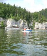 Barcos en un lago rodeado de acantilados y bosque en Camping Lac des Brenets, Neuchâtel, Suiza.