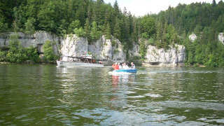 Barcos en un lago rodeado de acantilados y bosque en Camping Lac des Brenets, Neuchâtel, Suiza.