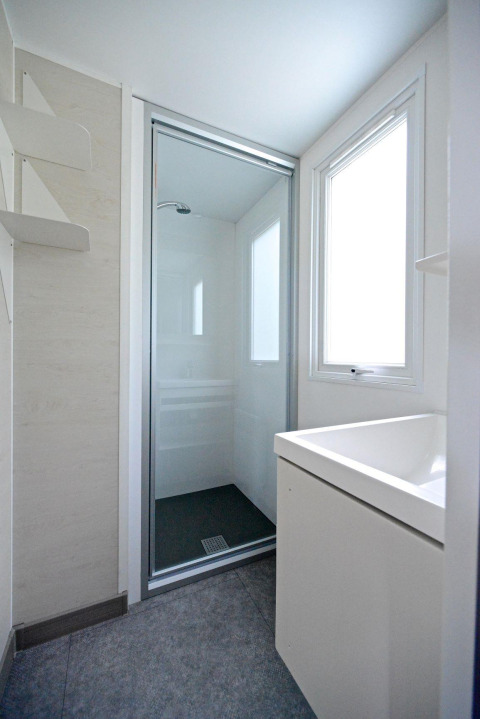 Lichte, moderne badkamer met douche en groot raam in een mobilhome bij Drau Camping Sachsenburg, Oostenrijk.