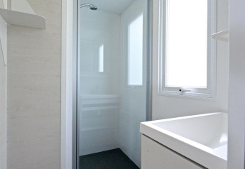 Lichte, moderne badkamer met douche en groot raam in een mobilhome bij Drau Camping Sachsenburg, Oostenrijk.