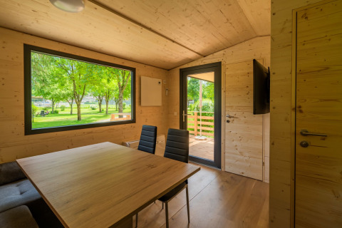 Intérieur d’un lodge moderne à Wood Cubes, Drau Camping Sachsenburg, Autriche, vue sur arbres verts.