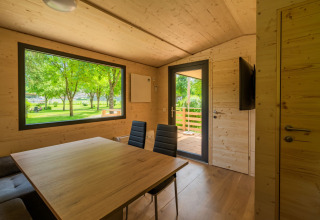 Interior de un lodge moderno en Wood Cubes, Drau Camping Sachsenburg, Austria, con vistas a árboles verdes.