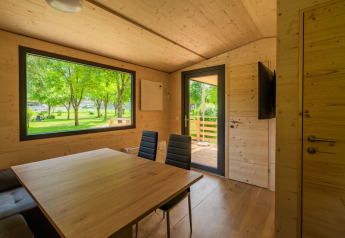 Innenraum einer modernen Lodge bei Wood Cubes, Drau Camping Sachsenburg, mit Blick auf grüne Bäume.