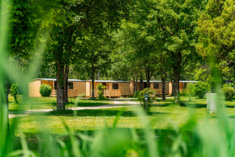 Houten huisjes Wood Cubes op Drau Camping Sachsenburg in Oostenrijk tussen het groen en bomen.