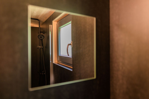 Riflesso di doccia e finestra in una moderna lodge presso Wood Cubes, Drau Camping Sachsenburg, Austria.