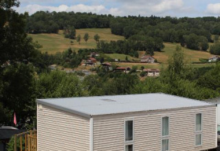 Mobile home O'Hara at Camping Lac des Brenets in Switzerland, surrounded by hills and countryside views.