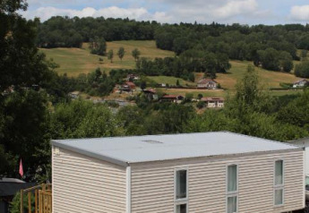 Stacaravan O'Hara op Camping Lac des Brenets in Zwitserland, omgeven door heuvels en groen landschap.