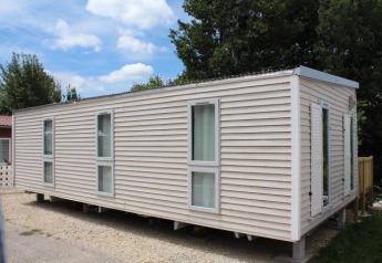 Mobilhome O'Hara på Camping Lac des Brenets i Schweiz, viser udvendig lyse facade og vinduer.