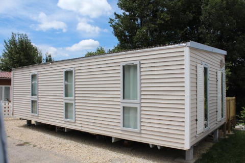 Mobilhome O'Hara på Camping Lac des Brenets i Schweiz, viser udvendig lyse facade og vinduer.