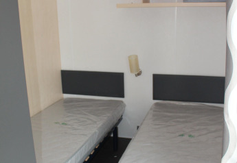 Bedroom with two single beds in a mobile home at Camping Lac des Brenets, Switzerland, with clean mattresses.
