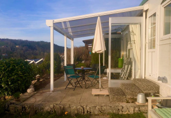 Terrasse ensoleillée du mobil-home Lavandou avec table, chaises et vue panoramique sur les collines.